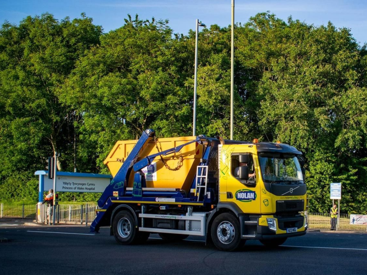 Nolan Recycling Ltd skip lorry in front of The Princess of Wales Hospital delivering a builders skip in Bridgend